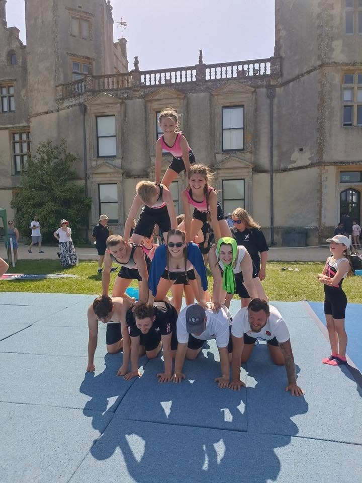 Gryphon West gymnasts forming a human pyramid in front of Sherborne Castle