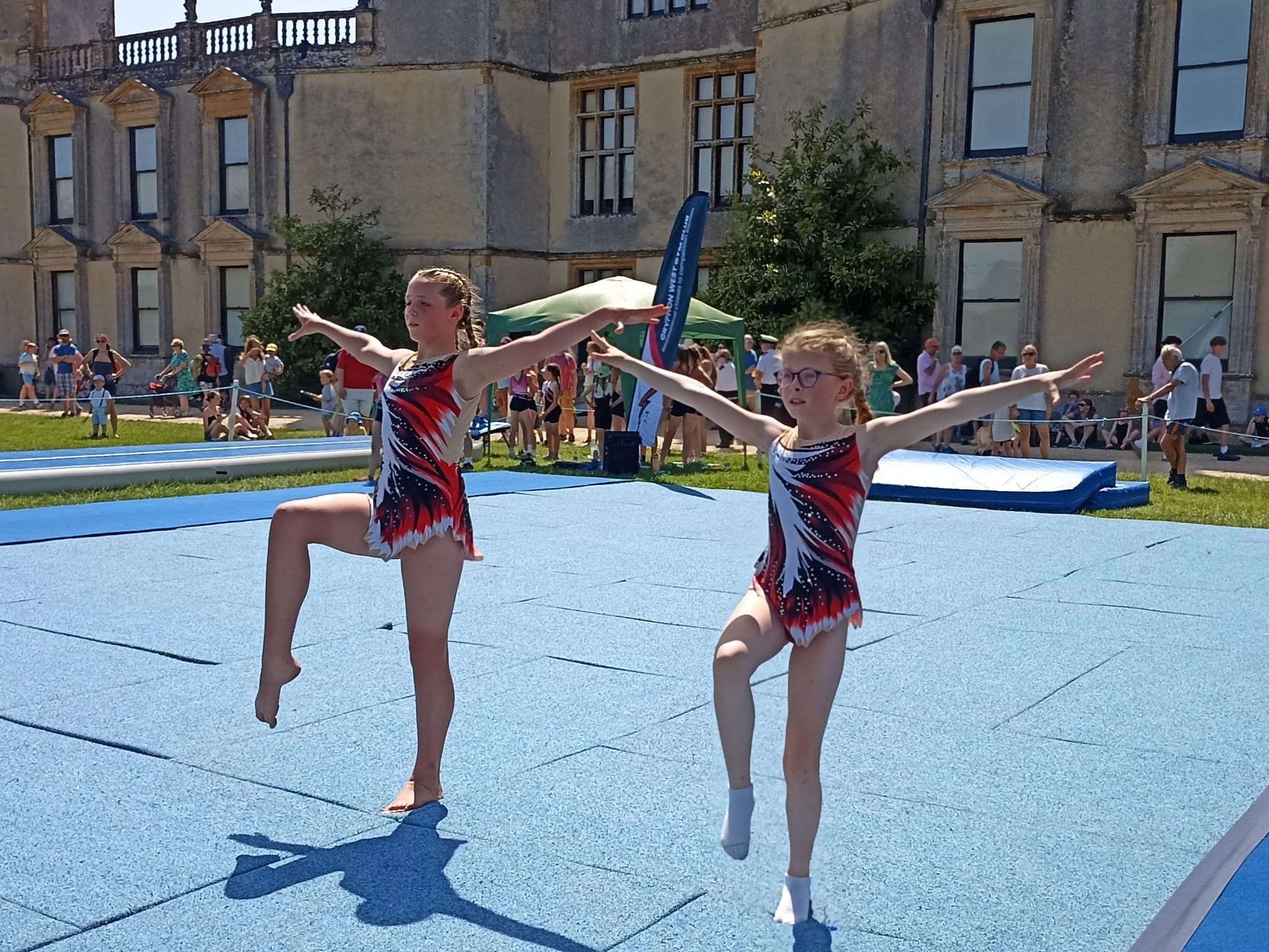Gryphon West squad marching onto the mat at Sherborne Castle in pink and black leotards